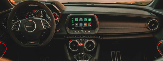 Car dashboard screen in a Chevrolet camaro showing the wireless Apple CarPlay interface with navigation maps and music widgets.