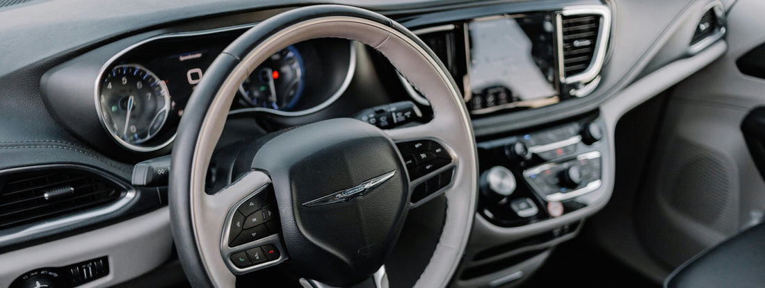 Close-up of a Chrysler's interior dashboard, steering wheel, and center console. The screen of vehicle infotainment system shows Apple CarPlay interface