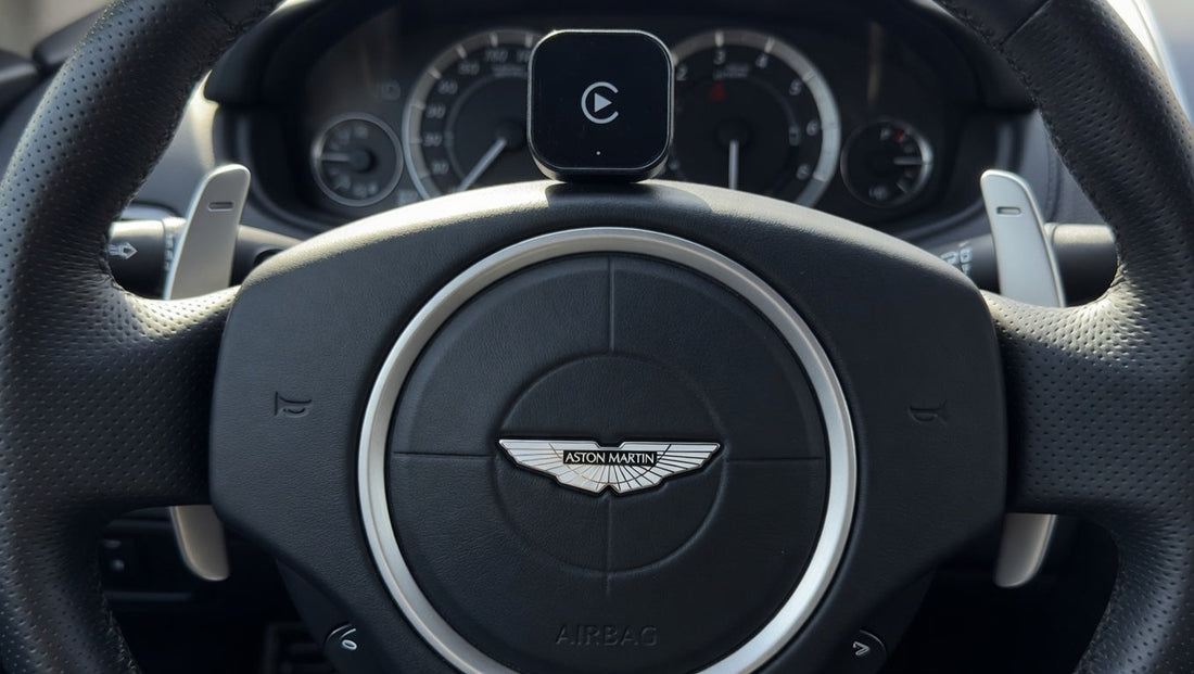 Wireless Apple CarPlay adapter placed inside an Aston Martin vehicle. Plug-and-play infotainment upgrade for compatible Aston Martin models with factory wired CarPlay support.