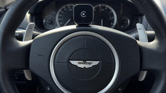 Wireless Apple CarPlay adapter placed inside an Aston Martin vehicle. Plug-and-play infotainment upgrade for compatible Aston Martin models with factory wired CarPlay support.