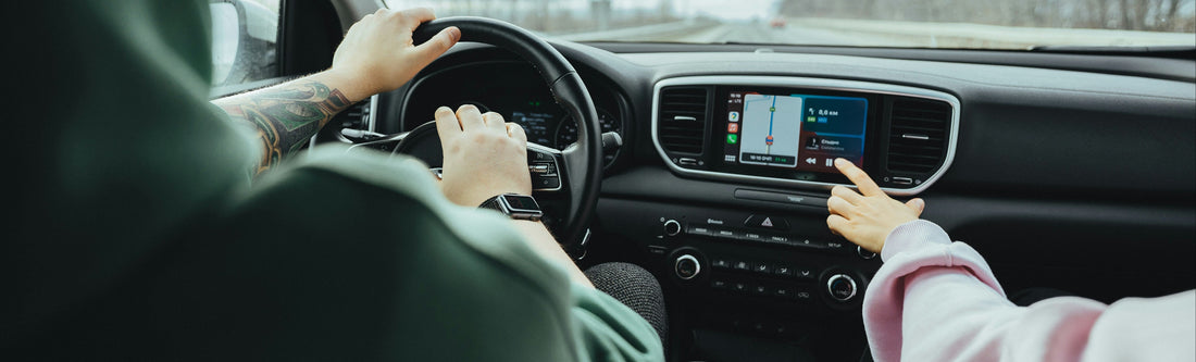 Two people inside a car, one driving and the other interacting with the vehicle's infotainment system choosing track on apple carplay screen